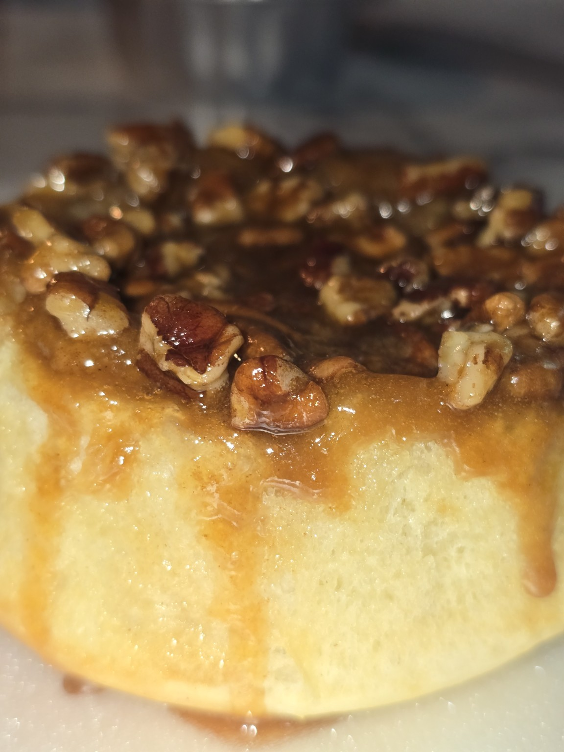 Close-up of a caramel pecan roll with glossy caramel glaze and pecan pieces