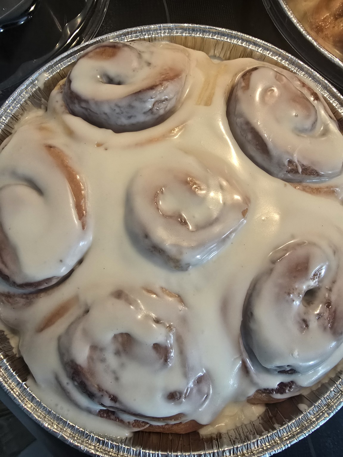 Pan of cinnamon rolls covered in creamy vanilla icing